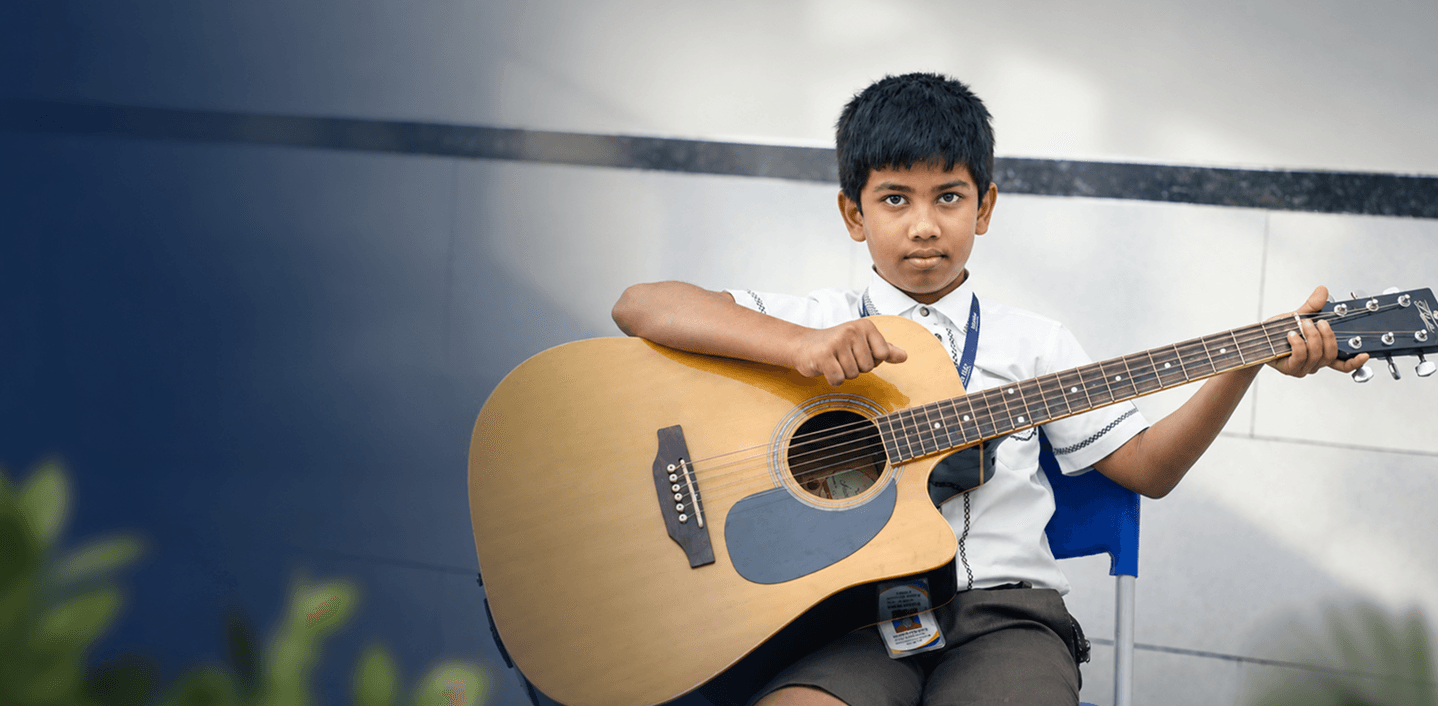 Student playing acoustic guitar in music class